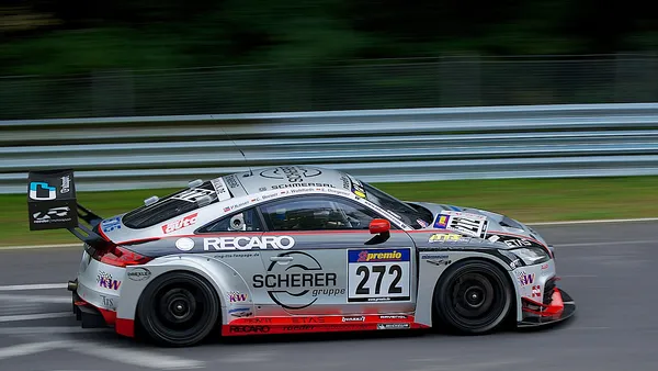 GT3 Mercedes-AMG amarelo cortando uma curva fechada do Nordschleife sob céu nublado alemão