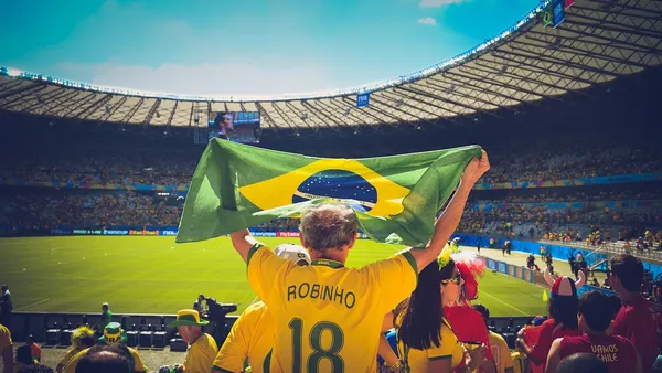 Torcedores com bandeira do Brasil em estádio de futebol