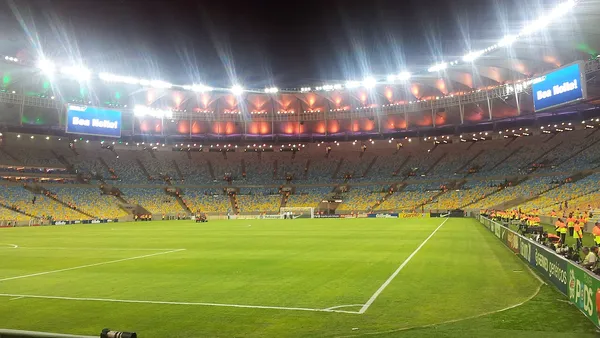 Estádio de futebol brasileiro à noite com torcida nas arquibancadas
