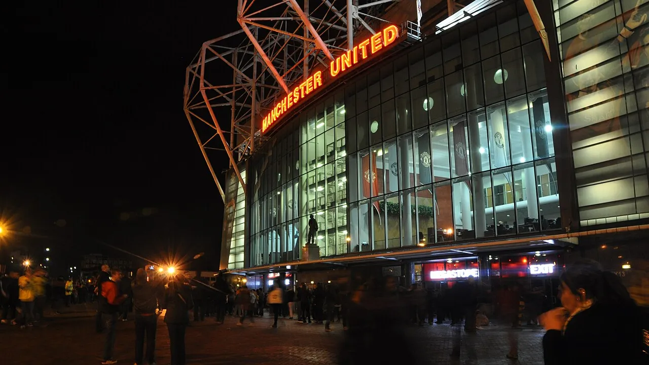 Banco de reservas vazio de um estádio de futebol inglês com gramado iluminado ao fundo