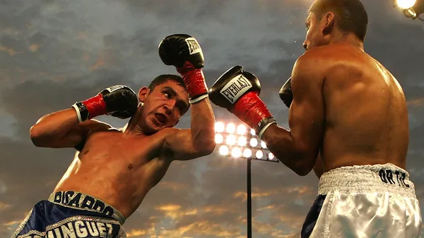 Lutador de MMA finalizando adversário no chão dentro do octógono iluminado