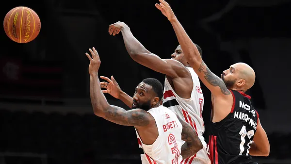 Quadra de basquete da NBA vista do alto com o logo da liga ao centro durante partida
