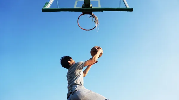 Jogador de basquete em enterrada durante partida em arena lotada