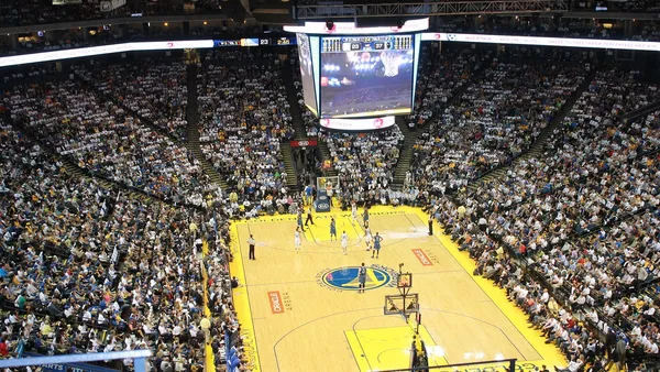 Quadra de basquete iluminada vista do alto durante jogo de playoffs