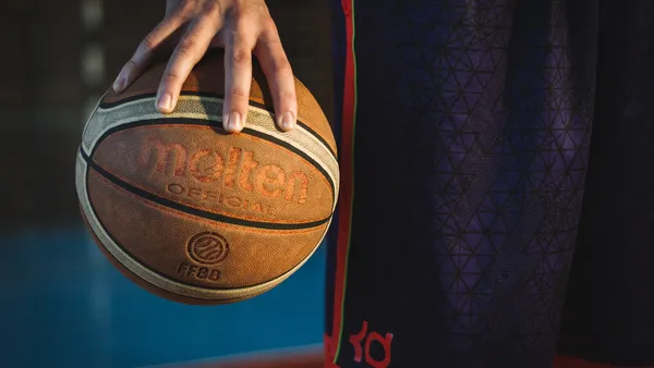 Jogador de basquete em close, dribbling com a bola laranja
