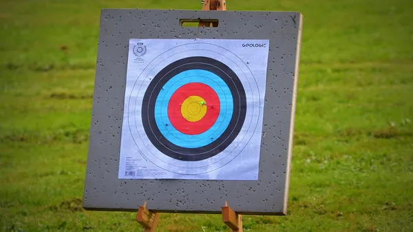 Arco recurvo apontado para alvo de competicao internacional, ilustrando a Copa do Mundo de tiro com arco
