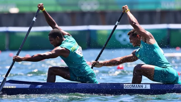 Isaquias Queiroz remando em canoa C1 com camisa azul do Brasil durante competição internacional de canoagem em raia tranquila.