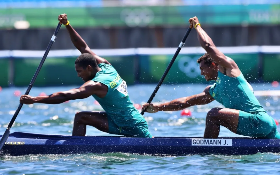 Isaquias Queiroz remando em canoa C1 com camisa azul do Brasil durante competição internacional de canoagem em raia tranquila.