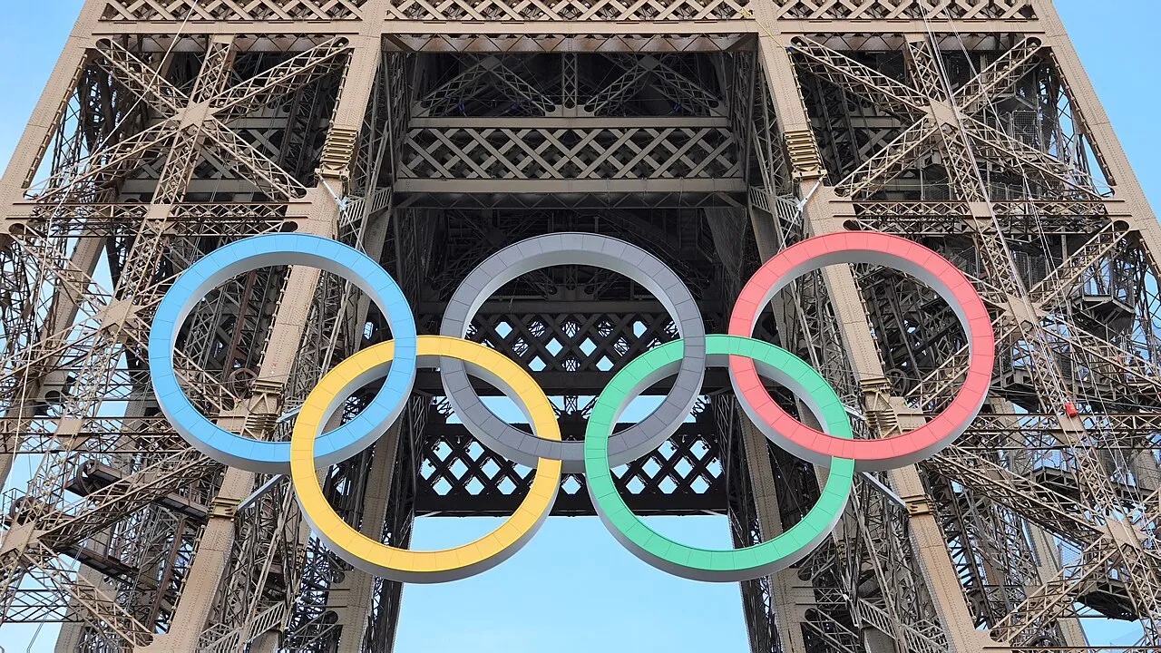 Tocha olímpica acesa em pista de atletismo, simbolizando o ciclo de qualificação rumo a Los Angeles 2028