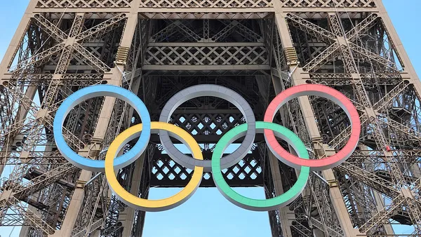 Tocha olímpica acesa em pista de atletismo, simbolizando o ciclo de qualificação rumo a Los Angeles 2028